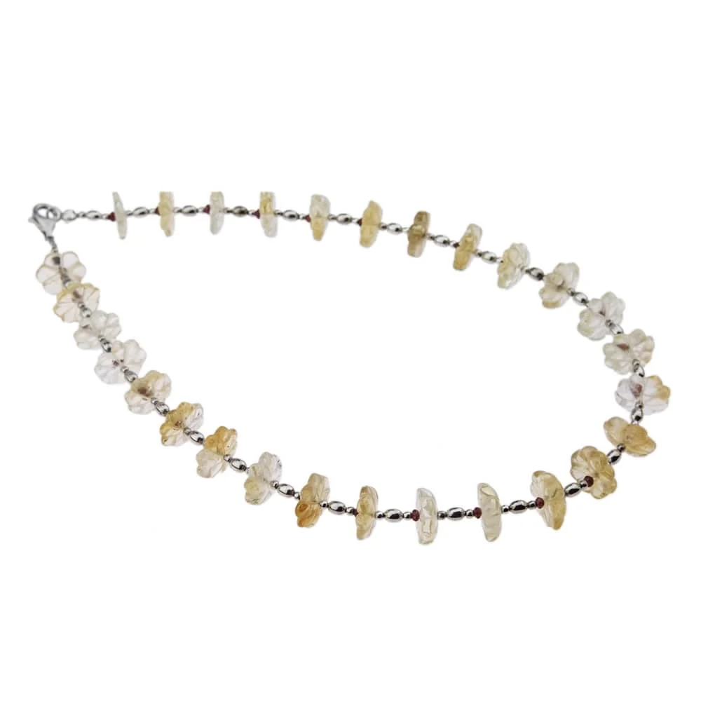 Un collier avec des fleurs en citrine et grenat fini par des apprêts en argent, ressemblant à des fleurs sur fond blanc.